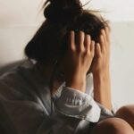 A-woman-sitting-on-the-floor-hands-on-her-head-reflecting-on-trauma-triggers-and-their-management